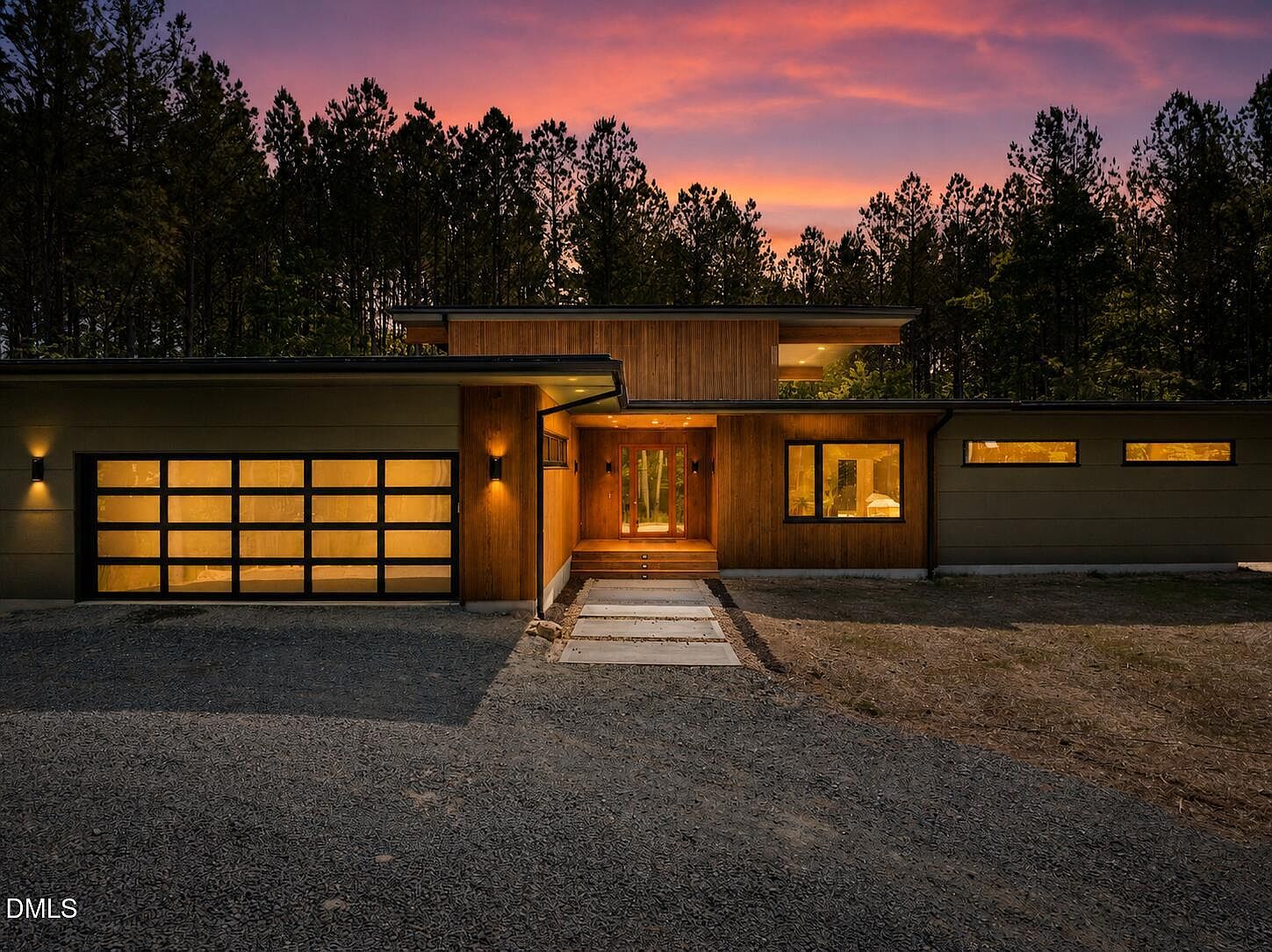 4637 Array Drive at dusk. The illuminated entry and warm cedar siding glow against a violet sky and tall North Carolina pines on a 1.52-acre wooded lot in Chapel Hill